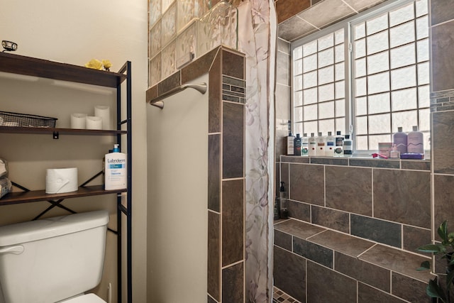 full bathroom featuring toilet and tiled shower