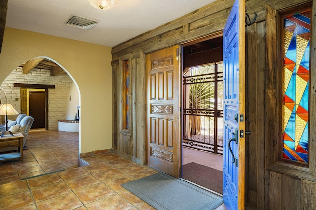 foyer with arched walkways, visible vents, and tile patterned floors