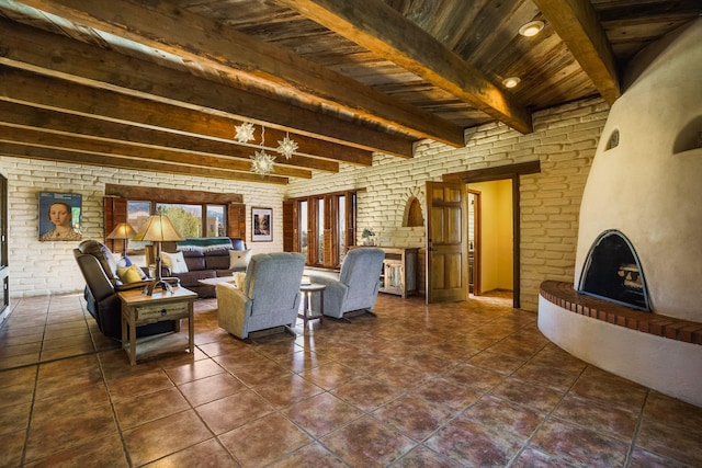 living area featuring beamed ceiling, dark tile patterned floors, wood ceiling, and brick wall