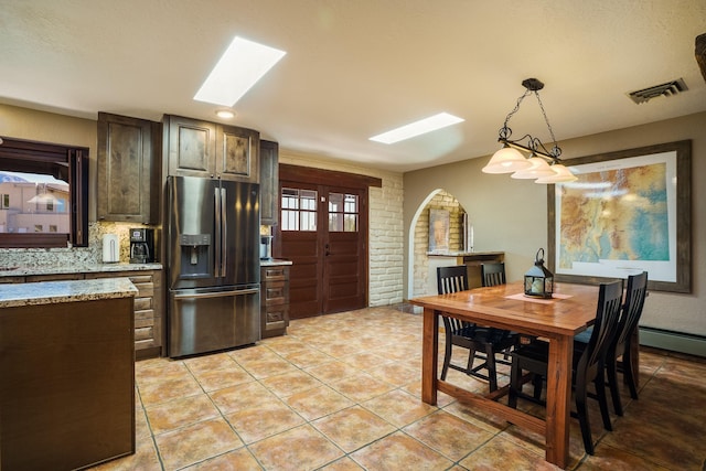 kitchen featuring light tile patterned floors, visible vents, stainless steel fridge, and a skylight