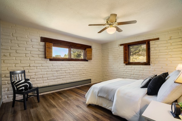 bedroom with a ceiling fan, wood finished floors, brick wall, a textured ceiling, and baseboard heating