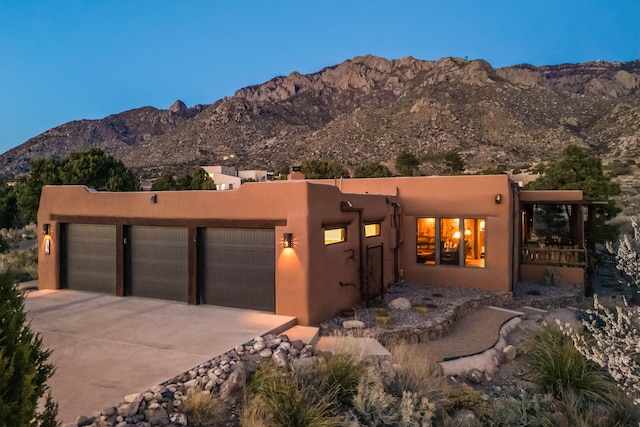 view of front facade with an attached garage, a mountain view, and driveway