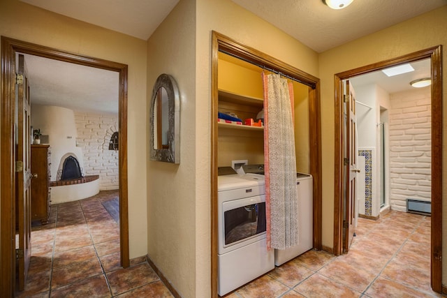 hall featuring brick wall, a baseboard heating unit, a textured wall, tile patterned floors, and independent washer and dryer