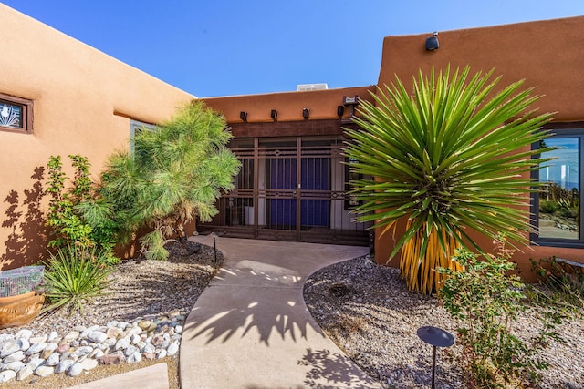 doorway to property with a gate, fence, and stucco siding