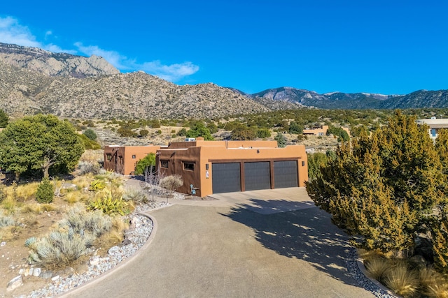 view of front of home featuring aphalt driveway, an attached garage, a mountain view, and stucco siding