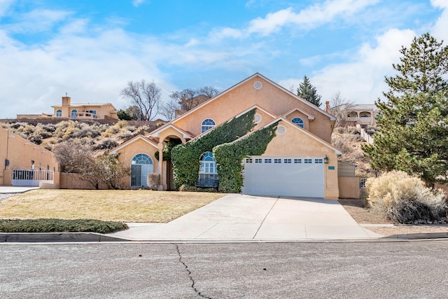 view of front facade featuring fence, driveway, and stucco siding