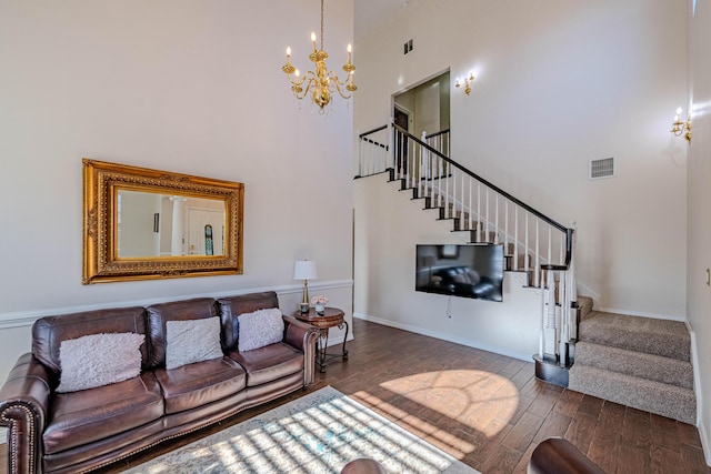 living room featuring visible vents, a chandelier, stairway, a high ceiling, and wood finished floors