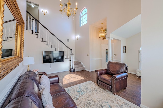 living area featuring stairway, wood finished floors, visible vents, baseboards, and an inviting chandelier