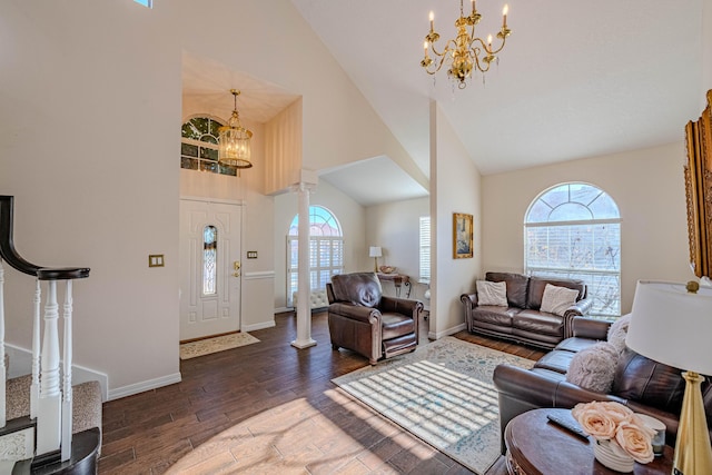 living area featuring high vaulted ceiling, wood finished floors, stairway, an inviting chandelier, and ornate columns