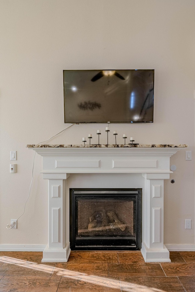 details featuring a fireplace, baseboards, and wood finished floors