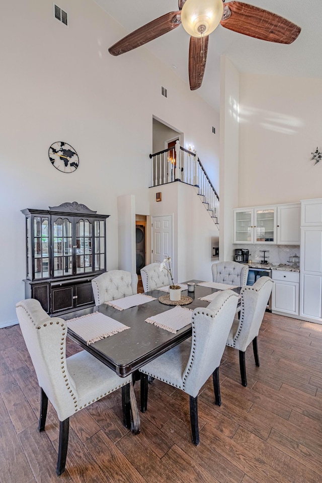 dining room featuring visible vents, high vaulted ceiling, dark wood-style floors, and a ceiling fan