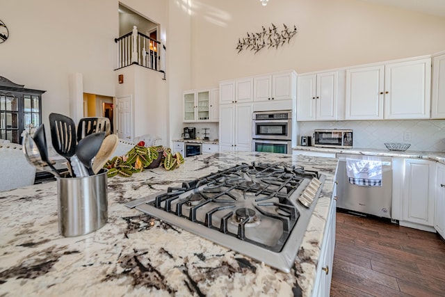 kitchen with dark wood finished floors, white cabinets, stainless steel appliances, and light stone counters