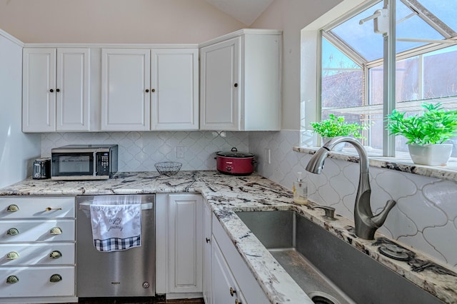 kitchen featuring a sink, stainless steel appliances, tasteful backsplash, and white cabinetry