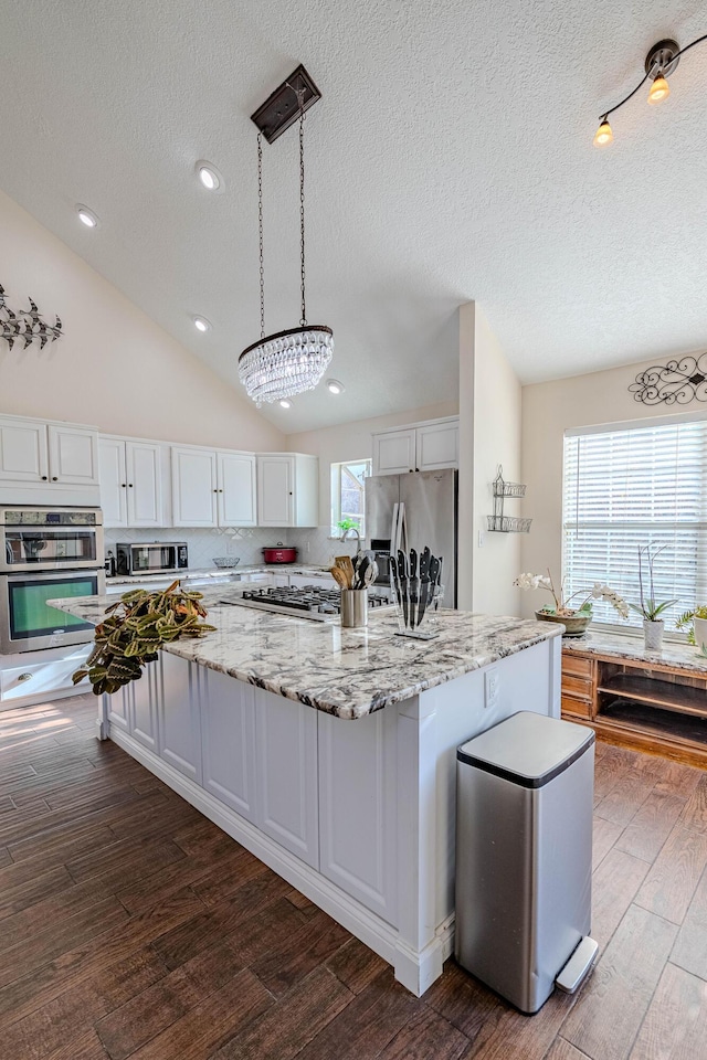 kitchen featuring lofted ceiling, white cabinets, dark wood-style flooring, and appliances with stainless steel finishes