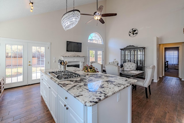 kitchen featuring light stone counters, white cabinetry, french doors, stainless steel gas stovetop, and dark wood-style flooring