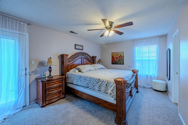 bedroom with visible vents, a textured ceiling, carpet, and a ceiling fan