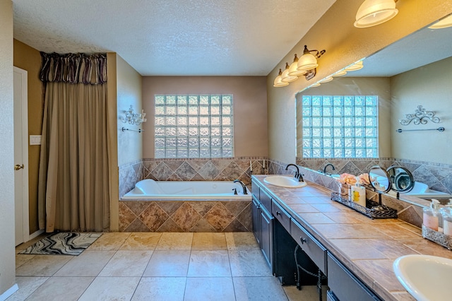 bathroom with a sink, plenty of natural light, a textured ceiling, and double vanity