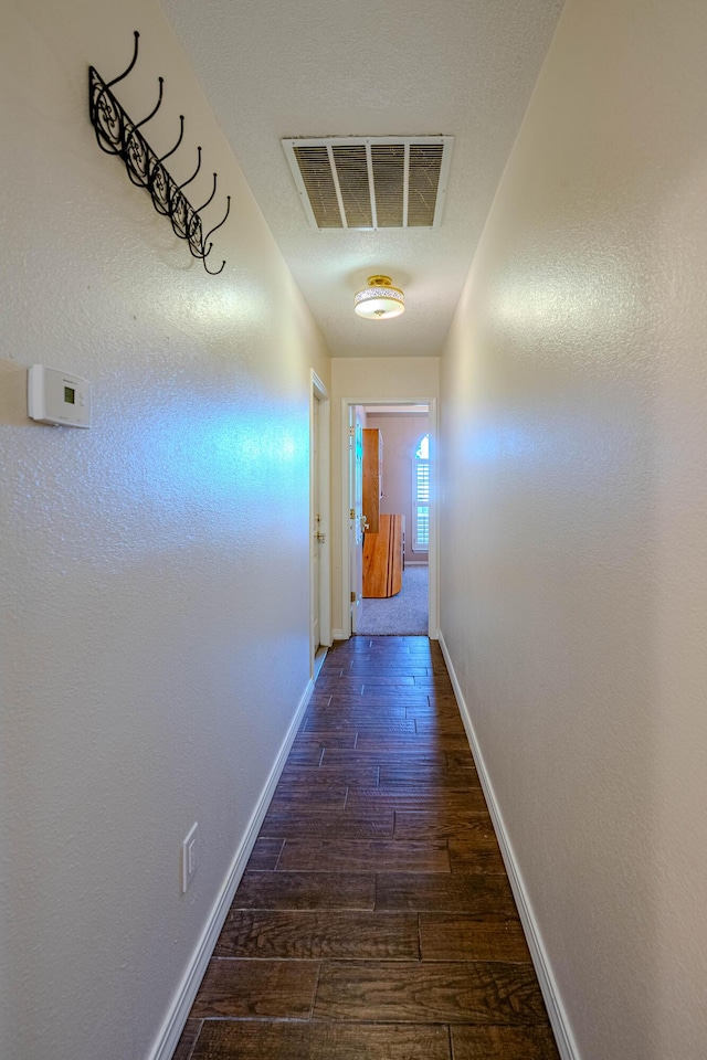 corridor with visible vents, baseboards, and wood finished floors