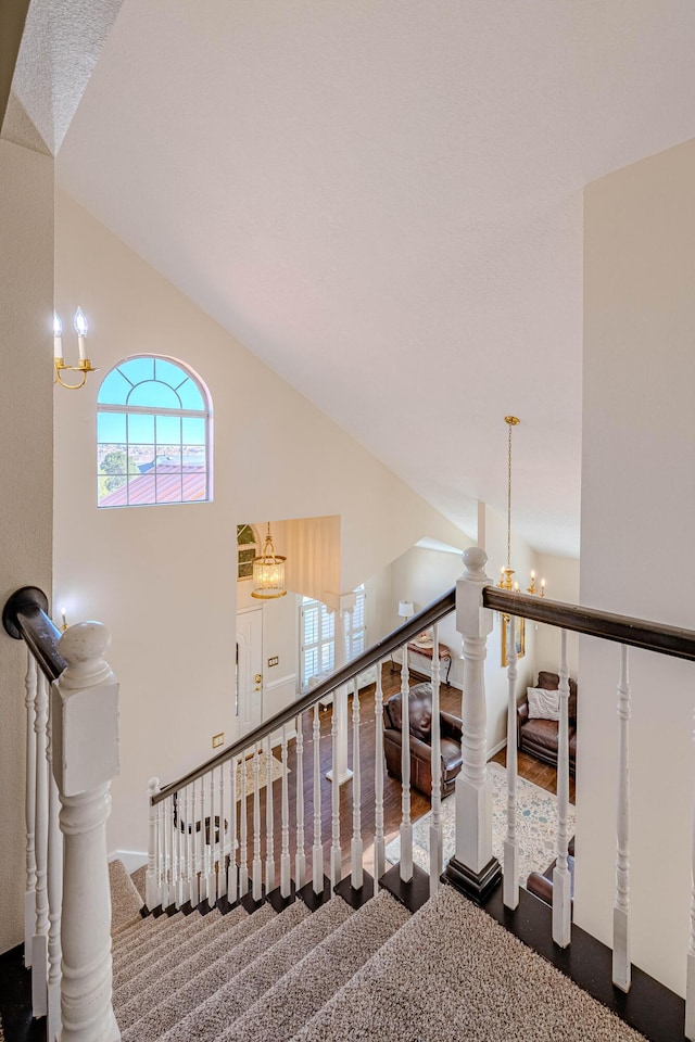 staircase featuring high vaulted ceiling, carpet flooring, and a chandelier