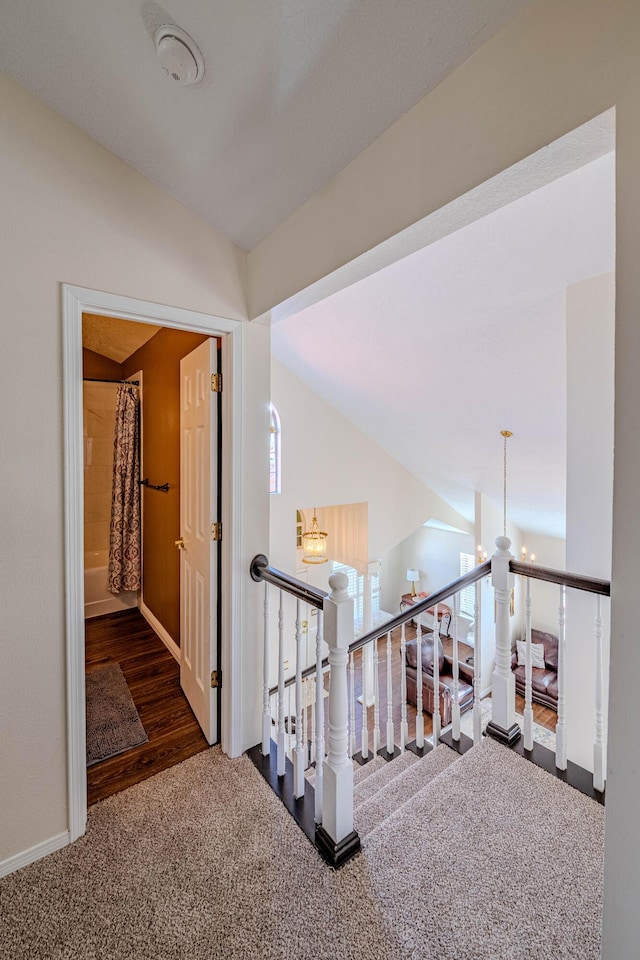 hallway featuring an upstairs landing, carpet, a chandelier, and vaulted ceiling