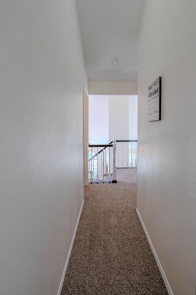 corridor with baseboards and carpet