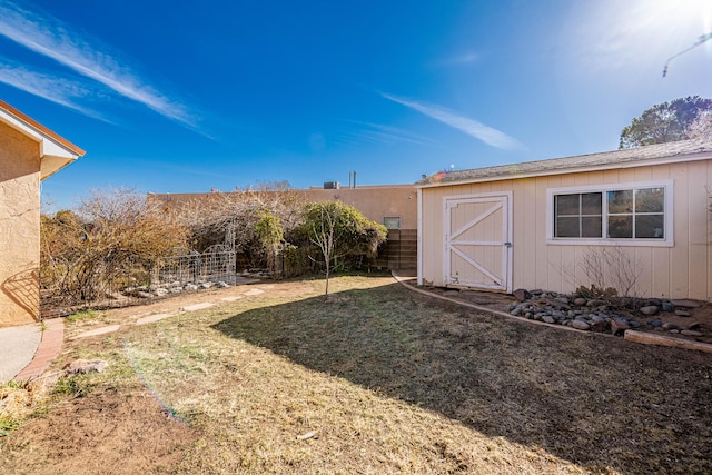 view of yard with a storage shed, an outdoor structure, and fence