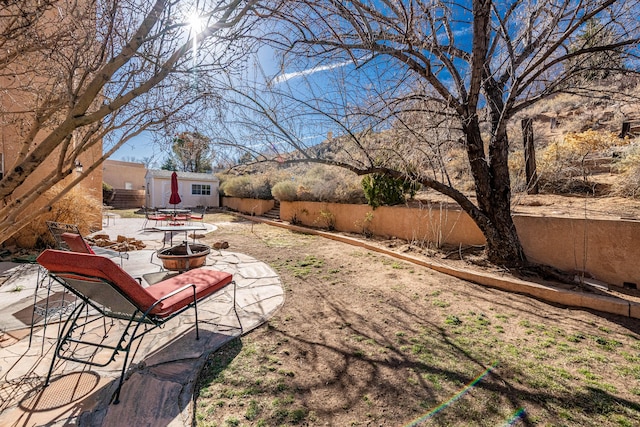 view of yard with a fire pit, an outbuilding, a fenced backyard, and a patio area