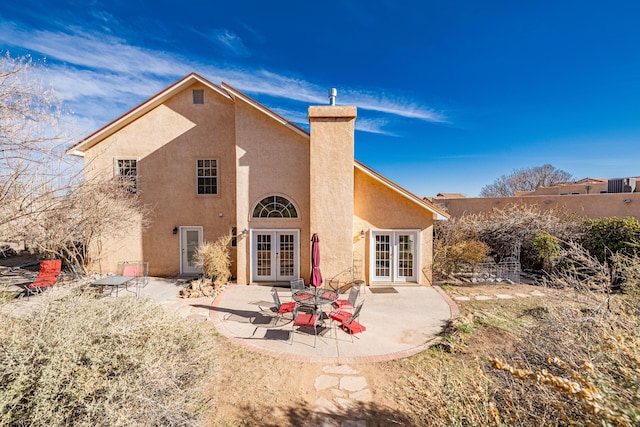 rear view of property with a patio area, french doors, a chimney, and stucco siding