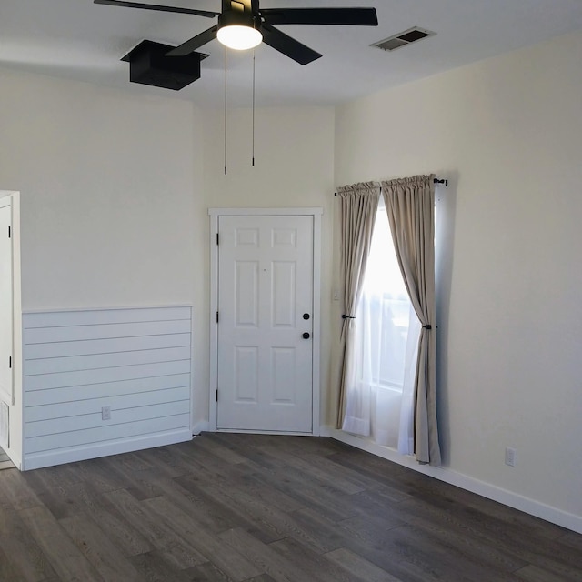 empty room with visible vents, baseboards, dark wood-style floors, and a ceiling fan