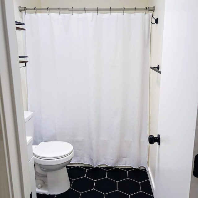 full bath featuring a shower with shower curtain, toilet, and tile patterned floors