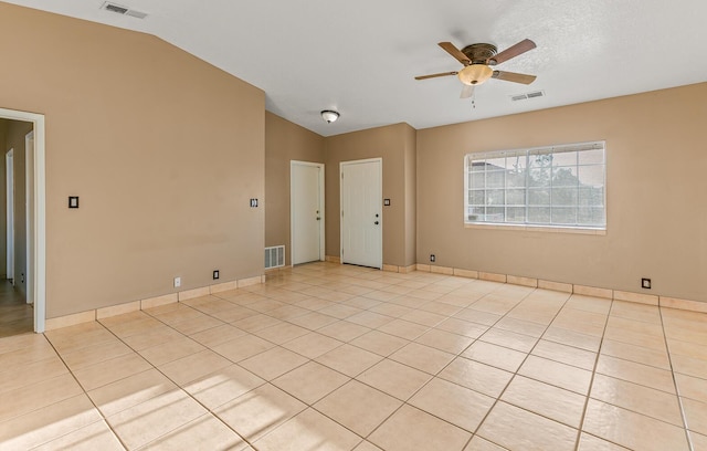 empty room with vaulted ceiling, light tile patterned floors, and visible vents