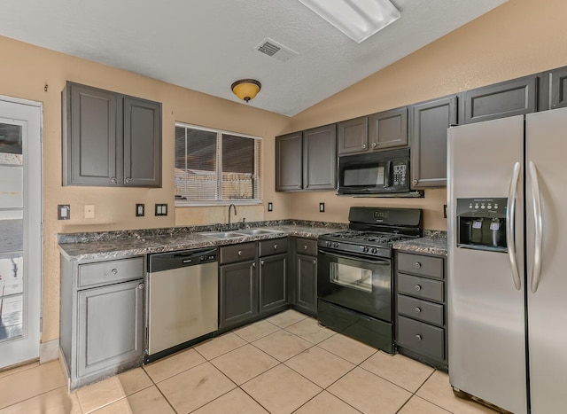 kitchen with visible vents, black appliances, a sink, dark countertops, and vaulted ceiling