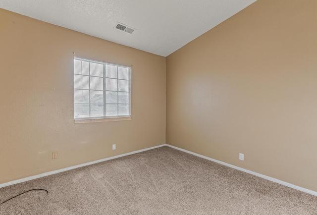 empty room featuring visible vents, lofted ceiling, a textured ceiling, carpet, and baseboards