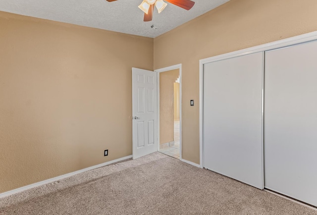 unfurnished bedroom featuring a ceiling fan, a textured ceiling, a closet, carpet floors, and baseboards