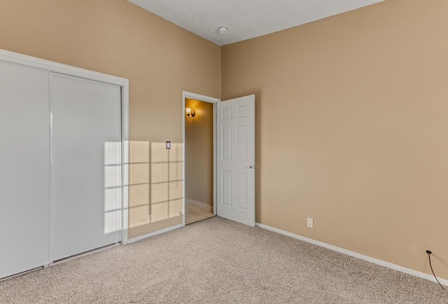 unfurnished bedroom with a closet, carpet flooring, a textured ceiling, and baseboards