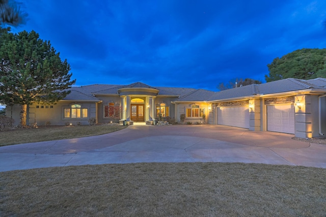 prairie-style home featuring a front lawn, concrete driveway, french doors, and a garage