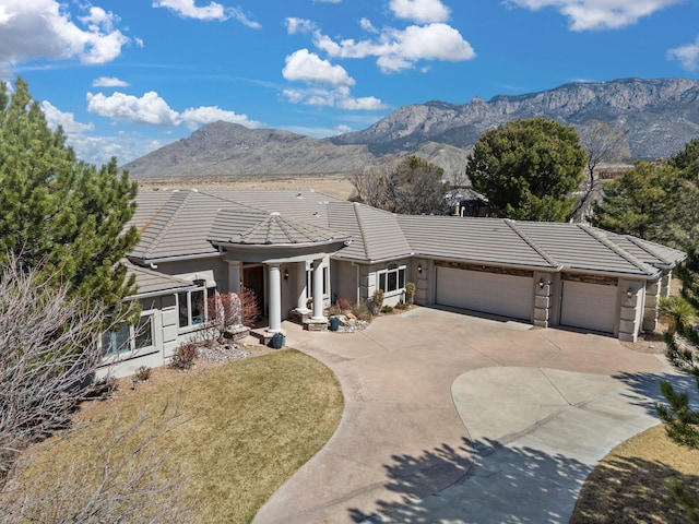 view of front of house featuring a garage, concrete driveway, a mountain view, and a tile roof