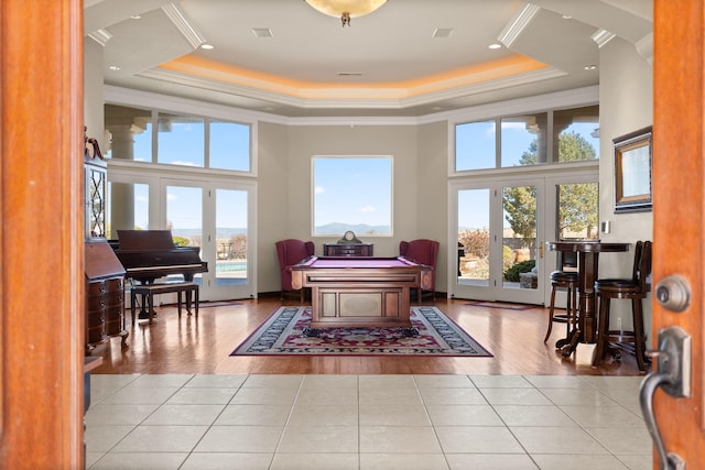 rec room with tile patterned floors, plenty of natural light, and a tray ceiling