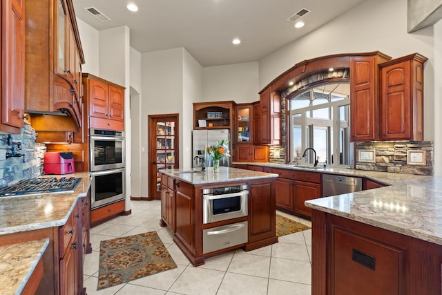 kitchen featuring light stone counters, visible vents, a sink, stainless steel appliances, and a warming drawer