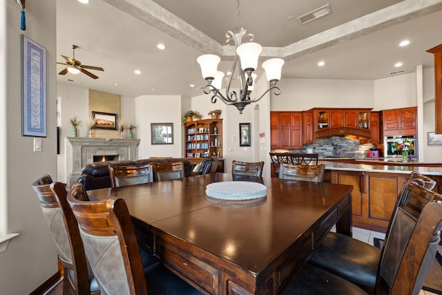 dining room with visible vents, a fireplace, recessed lighting, beamed ceiling, and ceiling fan with notable chandelier