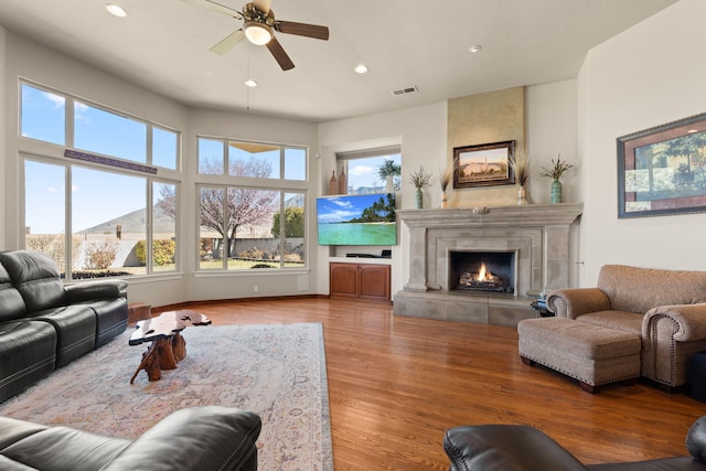 living area featuring wood finished floors, visible vents, recessed lighting, a tile fireplace, and ceiling fan