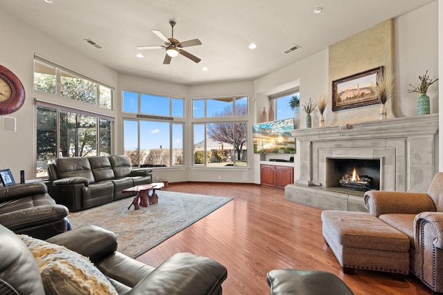 living area with a premium fireplace, recessed lighting, wood finished floors, and ceiling fan