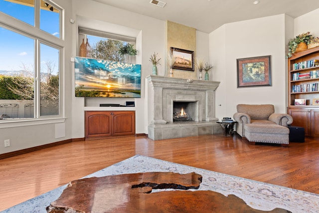 living room with visible vents, wood finished floors, baseboards, and a tile fireplace