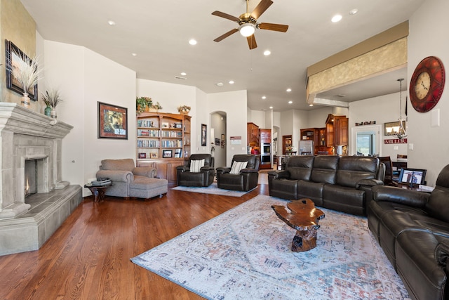 living area with recessed lighting, wood finished floors, a tile fireplace, and ceiling fan with notable chandelier