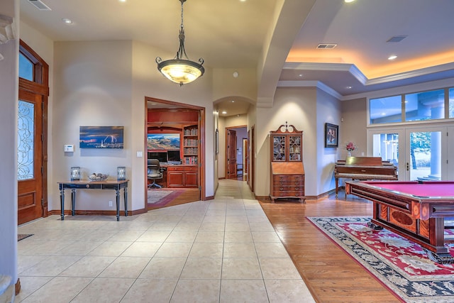 entrance foyer with visible vents, baseboards, a tray ceiling, light tile patterned flooring, and arched walkways