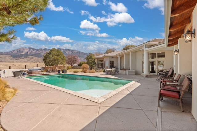 view of pool with french doors, a patio, a fenced in pool, and a mountain view