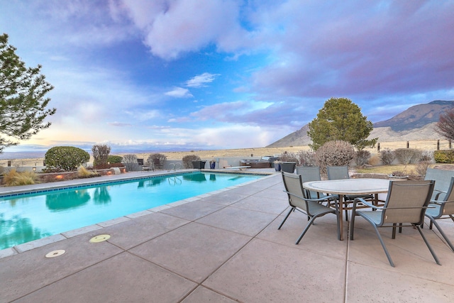 view of pool with a fenced in pool, outdoor dining space, a mountain view, and a patio area