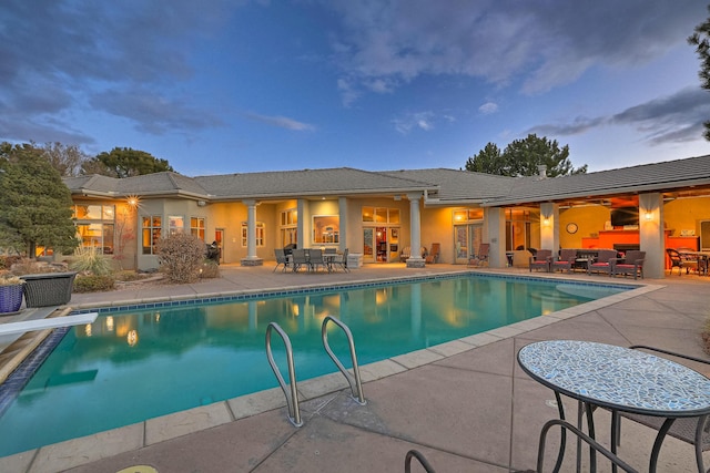 pool with outdoor dining area, a patio, and a diving board