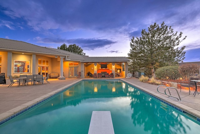 view of pool with a patio area, a fenced in pool, outdoor dining area, and a diving board