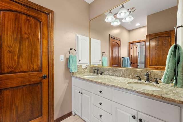 full bathroom with double vanity, baseboards, tasteful backsplash, and a sink